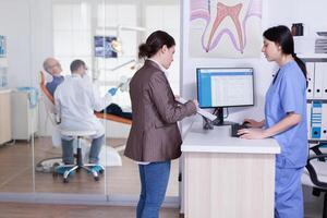 les patients demander informations remplissage dans dentaire document en train de préparer pour les dents examen. Sénior homme séance sur chaise pour traitement. dentisterie spécialiste traiter patient. photo