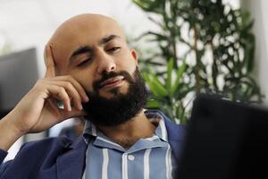 arabe entrepreneur discuter entreprise croissance stratégie dans appel vidéo en utilisant numérique tablette. exécutif directeur écoute à Ventes rapport présentation dans vidéo conférence appel dans Bureau photo