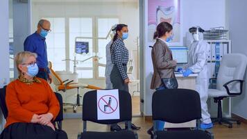 lent mouvement de les patients avec protection masque attendre dans bondé stomatologie accueil avec Nouveau normal, Personnel portant ppe costume. concept de Nouveau Ordinaire dentiste visite dans coronavirus épidémie. photo