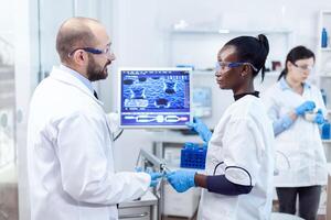 groupe de diverse soins de santé experts Faire virus examiner sur ordinateur. Multi-éthnique équipe de médical des chercheurs travail ensemble dans stérile laboratoire portant protection des lunettes et gants. photo