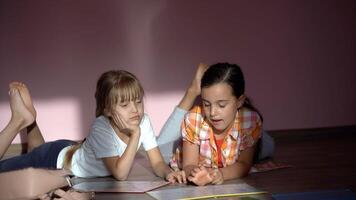 famille, loisir et enfance concept - content sœurs mensonge sur sol et Faire devoirs à Accueil photo