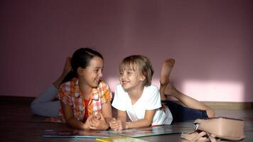 famille, loisir et enfance concept - content sœurs mensonge sur sol et Faire devoirs à Accueil photo