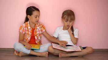 peu les filles en train de lire une livre dans vivant chambre. intelligent écolières Faire leur devoirs après école. éducation et distance apprentissage pour enfants. homeschooling pendant quarantaine. rester à Accueil divertissement. photo