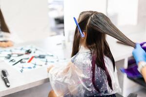 coiffeur colorants cheveux pour une peu fille dans une cheveux salon. teint, blanchi cheveux photo