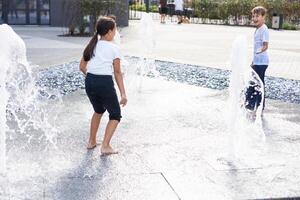 content adolescent fille dansant dans une Fontaine dans une ville parc sur une chaud été journée. photo