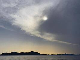 le Soleil est brillant par une nuageux ciel plus de le océan photo