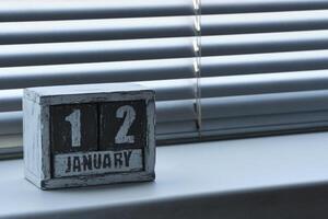 Matin janvier 12 sur en bois calendrier permanent sur fenêtre avec stores. photo