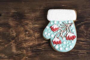 capricieux mitaine en forme de Noël biscuits, sorbier des oiseleurs arbre glaçage, neigeux accents, sur une rustique en bois toile de fond. photo