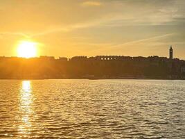 le Soleil est réglage plus de une ville et une corps de l'eau photo