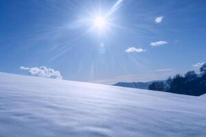 une la personne permanent sur une neigeux colline avec le Soleil brillant photo