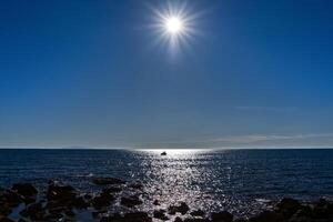 une pêcheur dans le océan contre le lumière photo