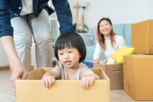 en mouvement loger, déménagement. famille sourire et content après acheter Nouveau appartement, à l'intérieur le pièce a été une papier carton boîte contenir personnel affaires et meubles. bouge toi dans le Nouveau appartement ou condominium photo