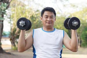 Beau asiatique homme des exercices Extérieur, ascenseur haltère. concept, exercice pour santé la musculation. renforcer muscle. poids levage. en bonne santé mode de vie. sport équipement. travail en dehors fait du fort de corps. photo