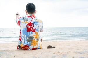 Jeune homme admiratif le mer et regards en dehors à mer de côtier. photo