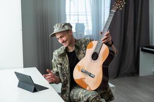 de bonne humeur souriant Jeune militaire homme portant kaki uniforme en portant guitare. photo