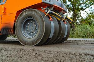 Orange rouleau compresseur pour asphalte avec quatre roues des stands sur le route à journée photo
