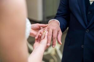 le la mariée porte une mariage bague sur le jeune marié photo