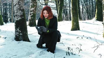 Jeune fille cueillette en haut neige de le neigeux sol dans le Montagne photo