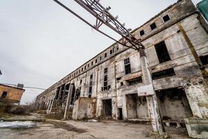 abandonné bâtiment avec brisé les fenêtres, usine extérieur. un vieux usine lequel mensonges abandonné dans le industriel centre dehors. photo