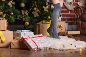 femme des stands sur la pointe des pieds dans une chaud guêtres sur une fourrure couverture dans le pièce près le Noël arbre avec présente photo