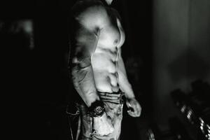 musclé Masculin torse sur noir Contexte. sélectif se concentrer. fort abdos, bodybuilder homme. noir et blanche. fermer. photo