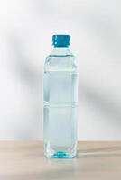 en buvant l'eau dans Plastique bouteilles sur une en bois table en dessous de le Matin lumière du soleil. photo