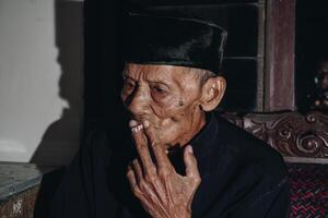 portrait de un personnes âgées asiatique homme fumeur une cigarette. photo