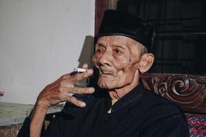 portrait de un personnes âgées asiatique homme fumeur une cigarette. photo