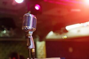 proche en haut de microphone sur étape à Extérieur nuit faire la fête, abstrait bokeh lumière Contexte photo