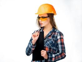 portrait de sérieux Jeune femme dans casque et sécurité des lunettes émouvant sa lèvres avec stylo et en pensant isolé. femelle architecte dans casque en portant noir dossier et une stylo à la recherche de côté photo