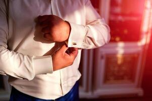 homme d'affaire Robes blanc chemise. jeune marié avoir prêt dans le Matin avant mariage cérémonie. Masculin mains proche en haut photo