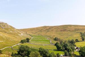 idyllique campagne paysage avec roulant collines, pierre clôtures, et vert pâturages en dessous de une clair ciel. photo