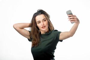 magnifique fille prise selfie sur blanc studio Contexte. poil long Jeune femelle prend une selfie sur sa téléphone intelligent. photo