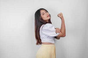 une portrait de asiatique femme montrant fort geste par levage sa bras et muscles souriant fièrement. photo