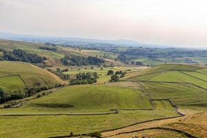 roulant collines avec patchwork des champs en dessous de une brumeux ciel, représentant rural les terres agricoles et Naturel beauté. photo