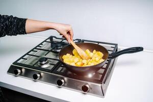 une femme friture patates dans le cuisine. frit Patate coins photo