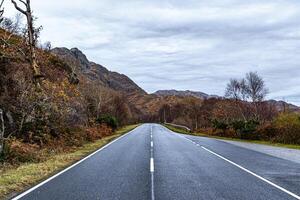 vide route élongation par une tranquille l'automne paysage avec coloré feuillage et Montagne toile de fond. photo