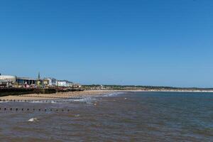 ensoleillé plage avec clair bleu ciel, calme mer, et une côtier ville dans le Contexte dans Bridlington, Angleterre. photo