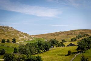 idyllique rural paysage avec vert des champs, pays route, et roulant collines en dessous de une clair bleu ciel. photo