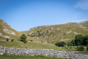 idyllique rural paysage avec pierre des murs et roulant collines en dessous de une clair bleu ciel. photo