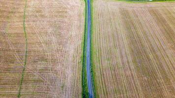 aérien vue de une rural paysage avec une étroit route partage agricole des champs. photo