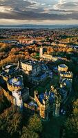 aérien vue de une historique lancaster Château à le coucher du soleil avec alentours jardins et loin paysage urbain. photo