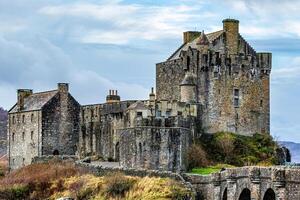 majestueux médiéval Château avec pierre pont en dessous de nuageux ciel dans Écosse. photo