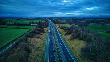 aérien vue de une Autoroute Coupe par une luxuriant campagne en dessous de une crépuscule ciel. photo