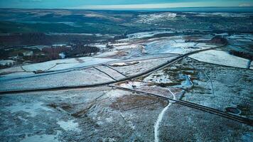 aérien vue de une neigeux paysage avec routes sécante par des champs et patchs de forêt. photo