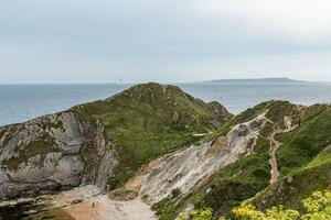 scénique côtier paysage avec robuste falaises, vert végétation, et une vue de le océan en dessous de une nuageux ciel. photo