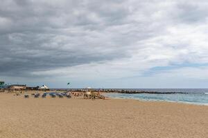 serein plage scène avec vide Soleil transats, calme mer, et couvert ciel, convoyer une paisible hors saison atmosphère dans los chrétiens, tenerife. photo