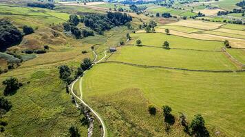 aérien vue de une enroulement pays route par vert des champs et pâturages avec patchwork paysage motifs. photo