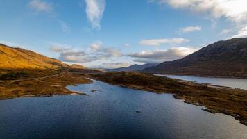 serein paysage avec une calme lac, roulant collines, et une clair ciel pendant d'or heure dans Écosse. photo