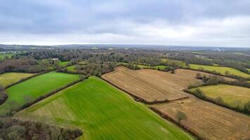 aérien vue de luxuriant vert les terres agricoles avec patchwork des champs en dessous de une nuageux ciel. photo